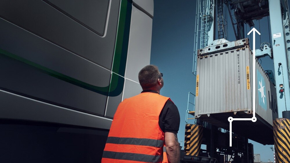 Worker watching container lifted by crane