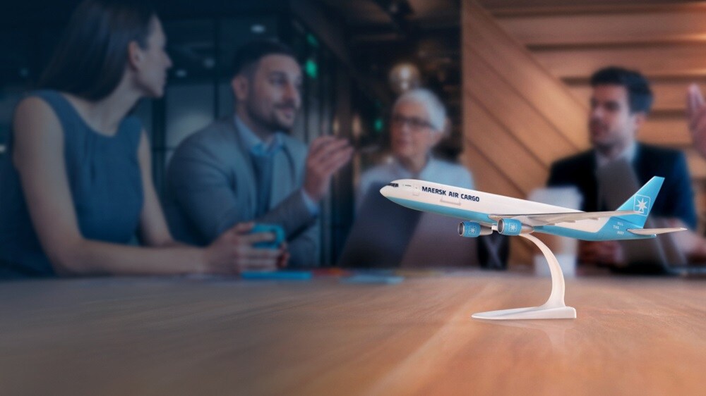Airplane dummy on a table will multiple people in the background