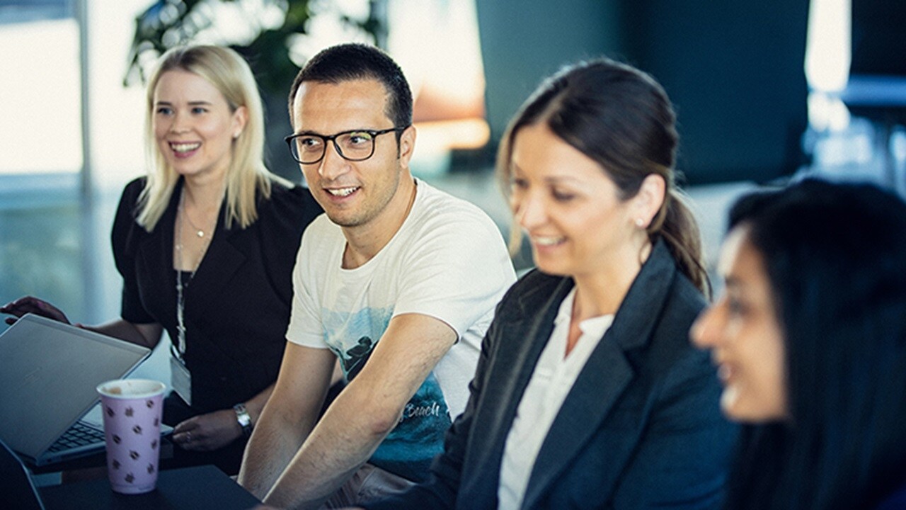 A team of smiling employees in a Maersk office.