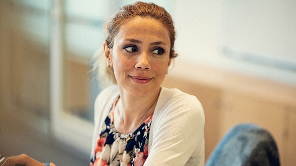 一位女性 UX 设计人员坐在工作站，微笑着看向她的左侧。