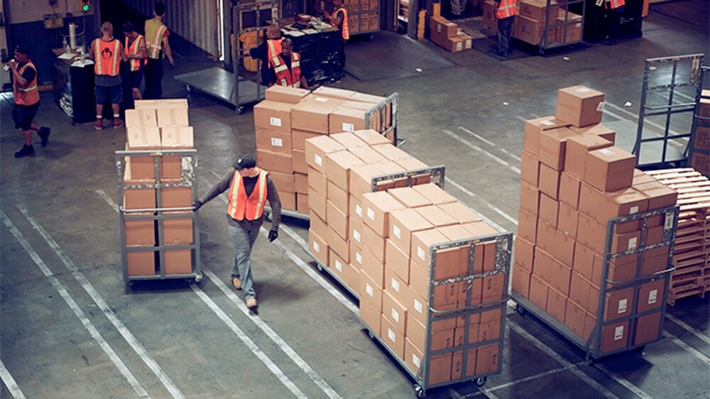 Person wearing orange jacket and working in warehouse