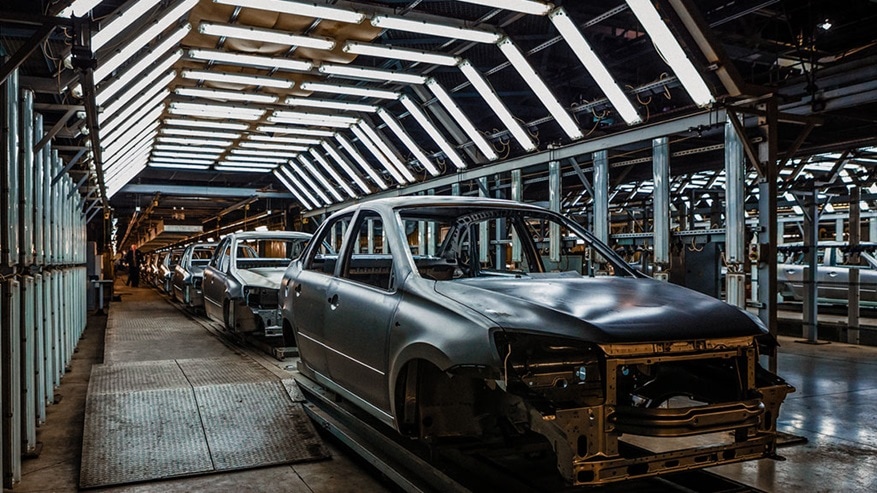 A row of cars in an assembly line.