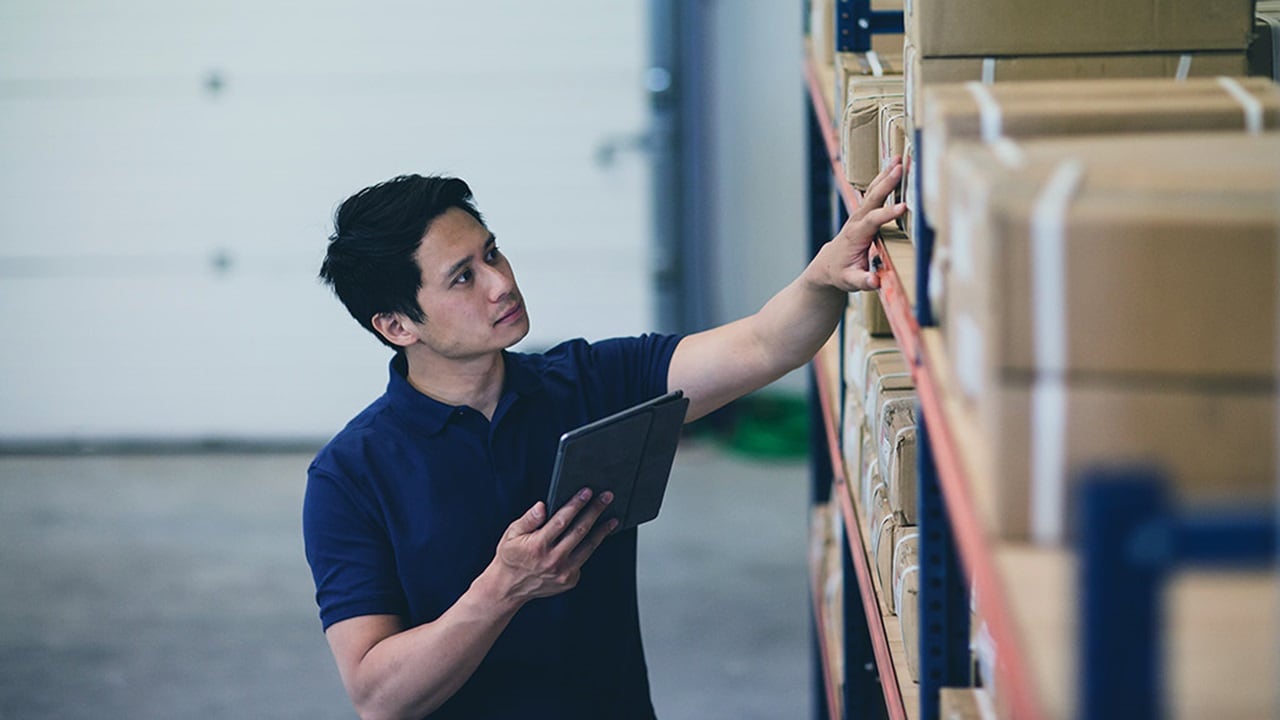 A male worker with a digital tablet checking the cargo in shelves.