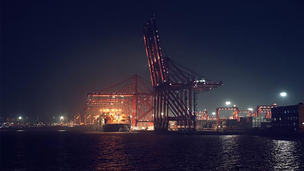 A shipping port unloading containers from a vessel
