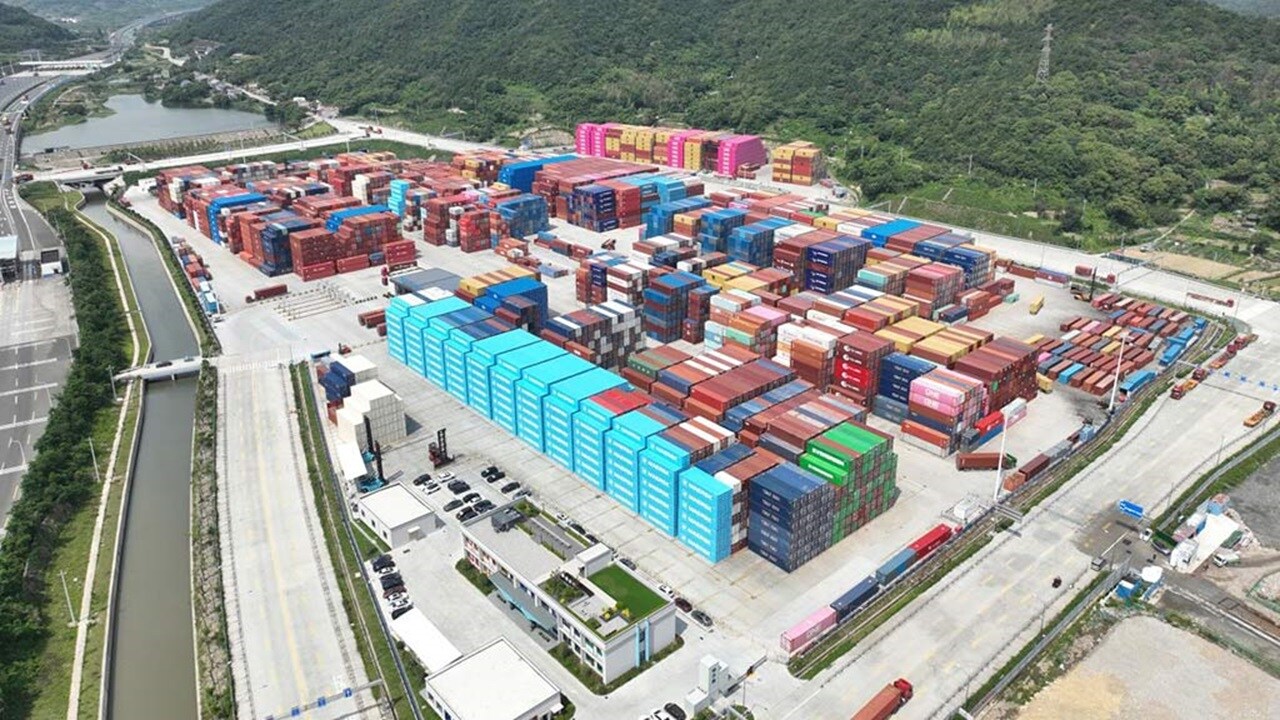 Aerial view of a large container depot yard with stacked shipping containers from multiple carriers
