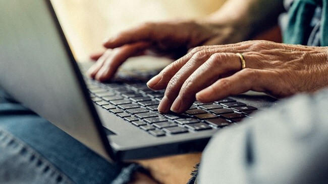 A person’s hands typing on a laptop