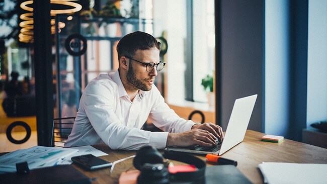 Man sitting a table typing on a laptop