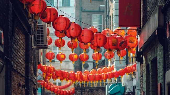 A picture showing multiple bright red Chinese lanterns lit across the street on the Chinese New Year.