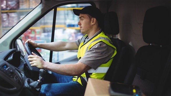 Man in a yellow vest driving a truck