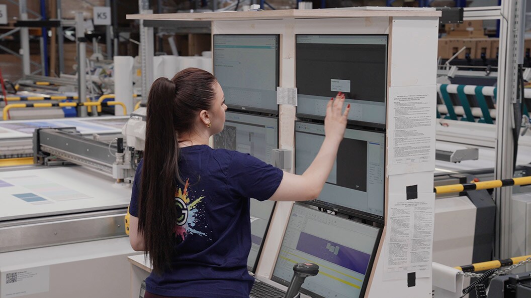 Person using multiple monitor screens in a manufacturing setup.