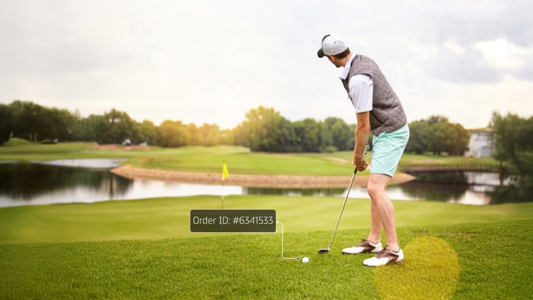 A man putting on a picturesque golf course with a water feature and verdant trees in the backdrop.
