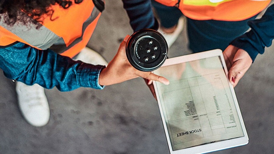 Retail employees have close-up of a hand on a Tab which is showcasing stock sheet.