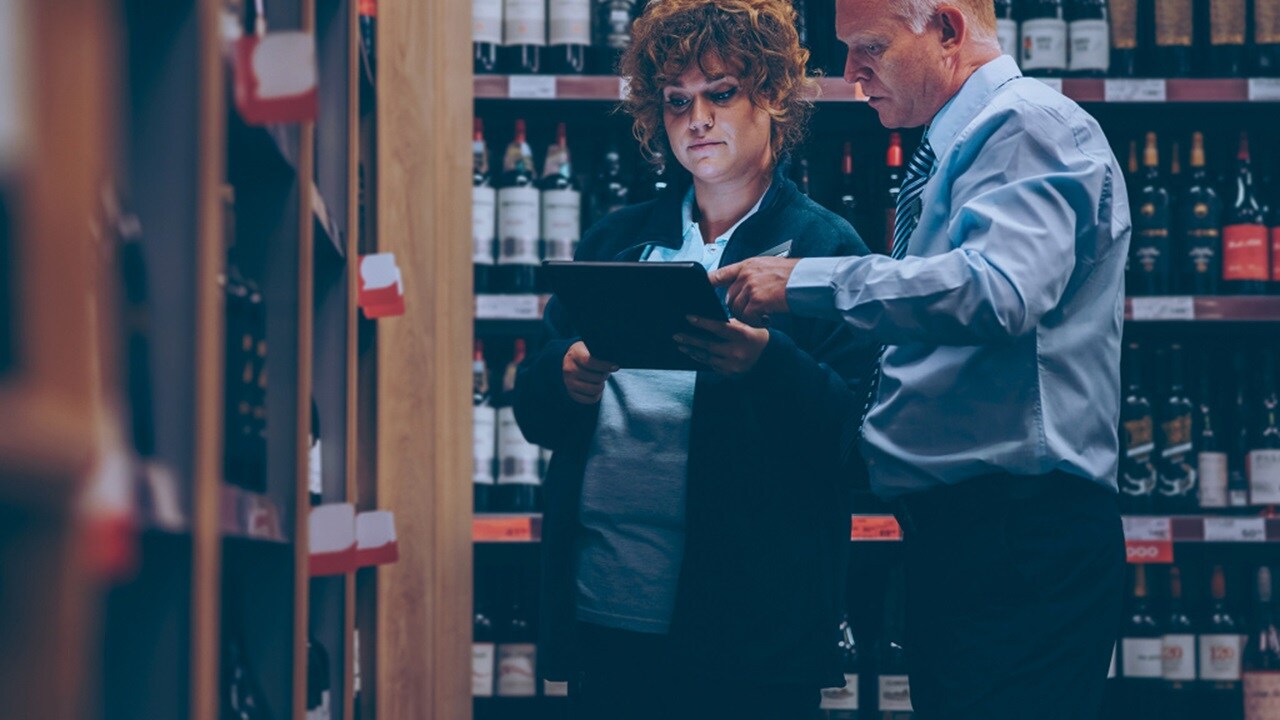 Store manager and sales woman cataloguing wine in a store