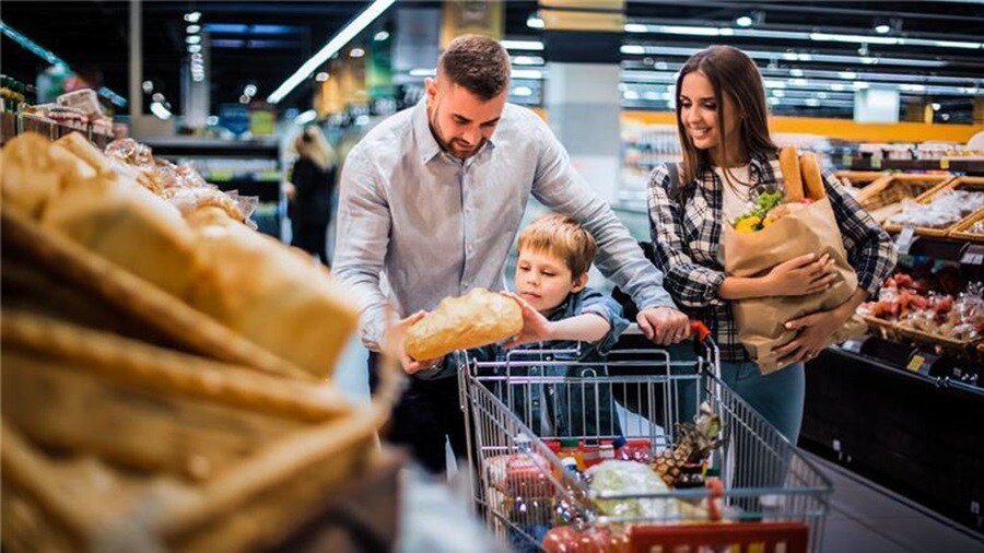 Jovem família feliz fazendo compras no supermercado