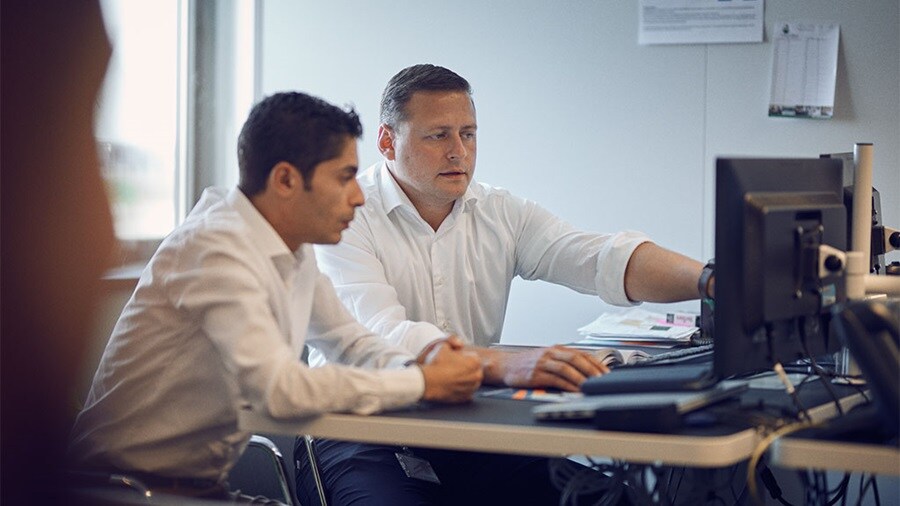 Two customs consultants working at a computer on customs clearance documents.