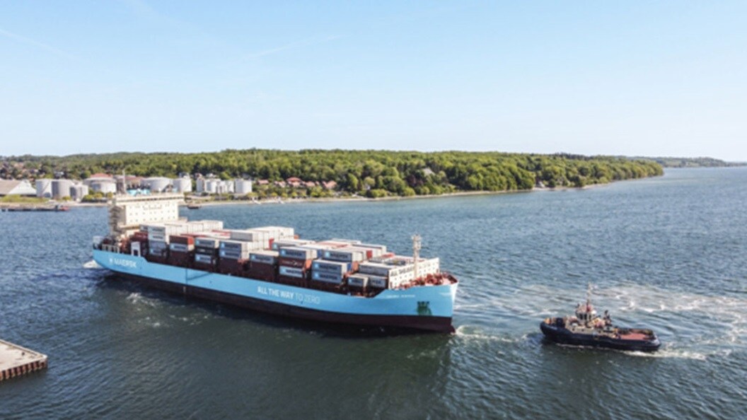 A large container ship is being towed by a tugboat across the water, showcasing maritime transportation in action.
