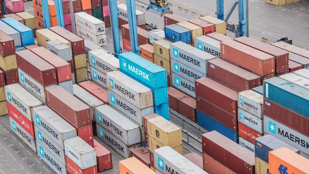 Vista aérea de un gran patio de contenedores lleno de coloridos contenedores de transporte dispuestos en filas ordenadas.