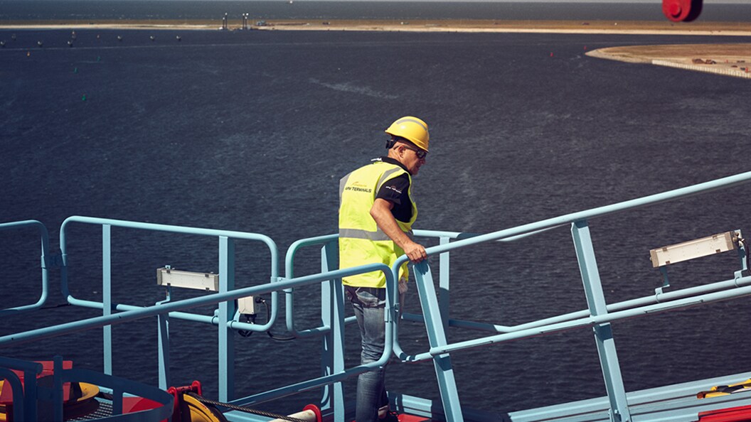Crane operator standing on top of a crane in a terminal.