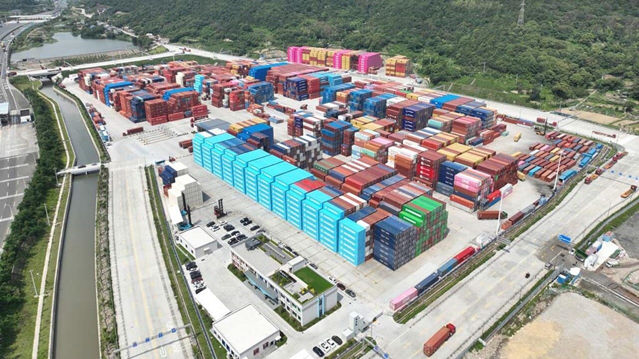 Aerial view of a large container depot yard with stacked shipping containers from multiple carriers.