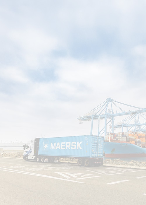 Maersk container truck at a port terminal beside a Maersk cargo ship being loaded with containers