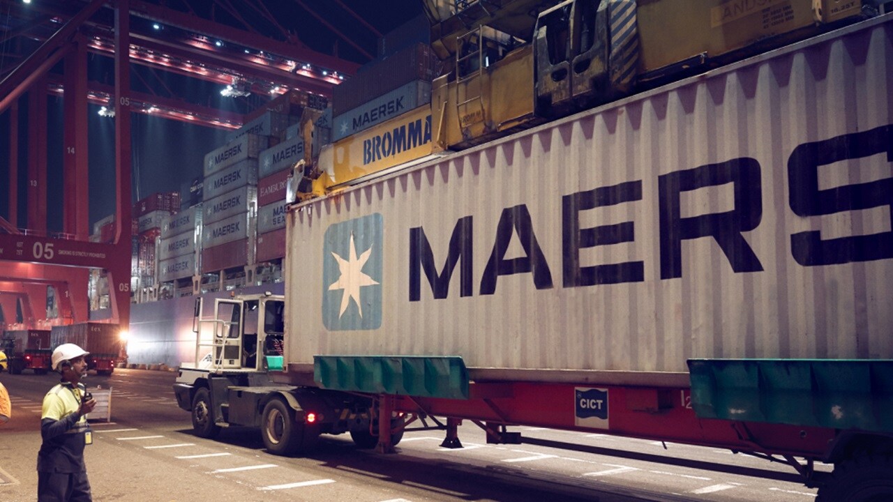 Вид сбоку грузового автомобиля с контейнерами Maersk премиум-класса, предназначенного для безопасной перевозки.